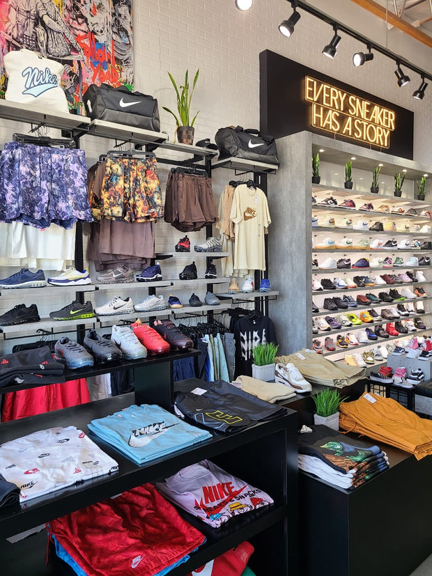 Sneaker store interior with shoes, apparel displays and "Every Sneaker Has A Story" sign