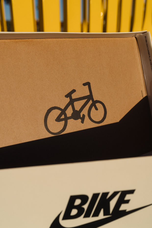 Nike SB "Bike" shoebox with bicycle logo and shadow on cardboard surface