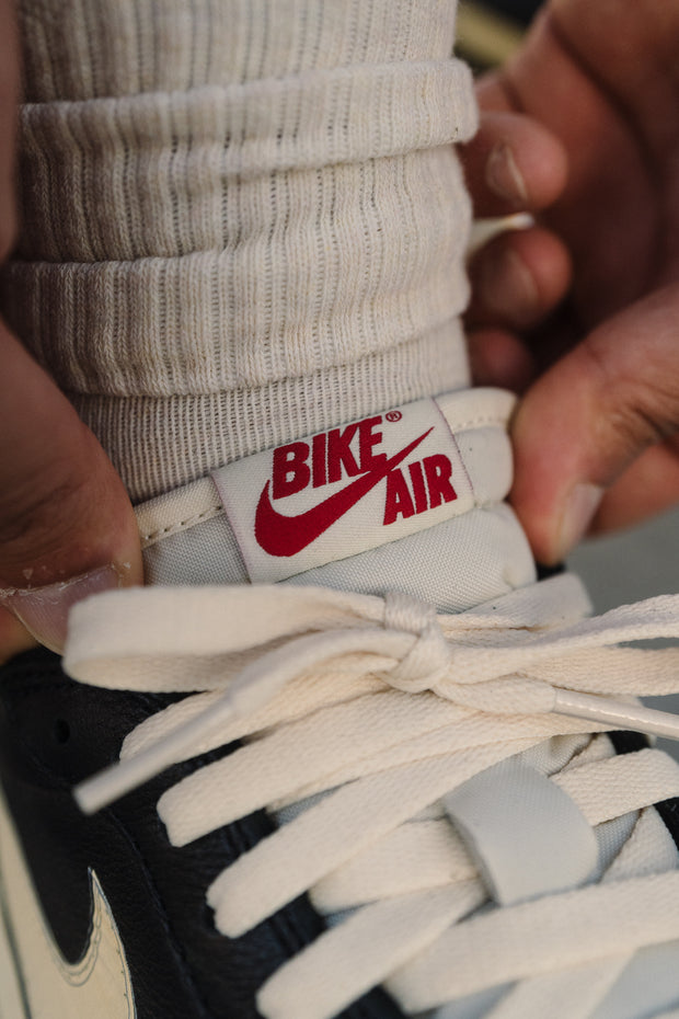 Close-up of "Bike Air" tongue label on black Nike sneaker with cream laces