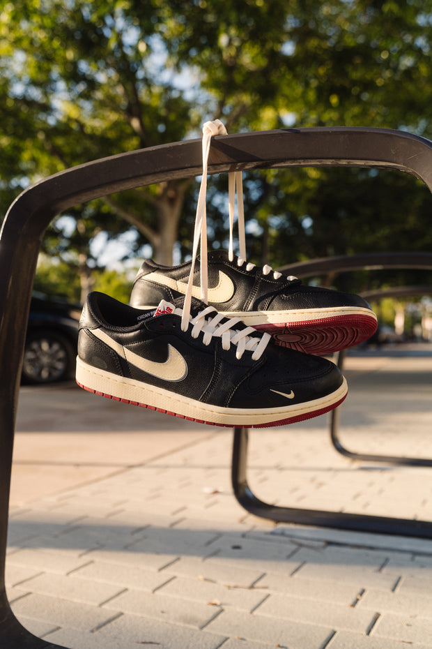 Black Nike SB Dunk Low sneakers hanging by laces on a bike rack outdoors