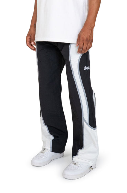 EPTM Cloud track pants in black and white with a wide-leg nylon finish, styled with white sneakers against a background.