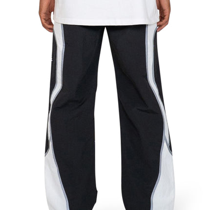 EPTM Cloud wide-leg joggers in black with bold white side panels and reflective piping, styled with white sneakers.