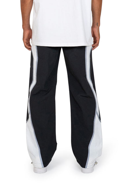 EPTM Cloud wide-leg joggers in black with bold white side panels and reflective piping, styled with white sneakers.
