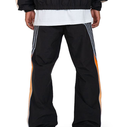 EPTM Proxy pants in black technical fabric featuring side gray stripes and orange accents, viewed from the rear.