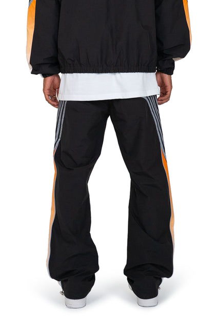 EPTM Proxy pants in black technical fabric featuring side gray stripes and orange accents, viewed from the rear.