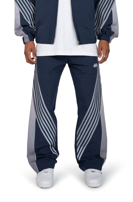 EPTM Proxy track pants in navy featuring grey side panels and sweeping diagonal striped detailing on both legs.