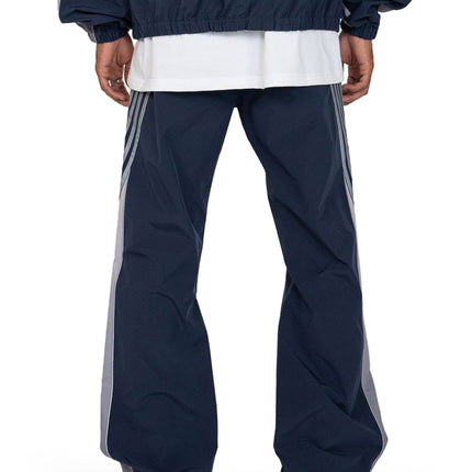 Rear view of navy EPTM Proxy pants featuring light gray side stripes and a relaxed fit in a smooth, matte finish fabric.