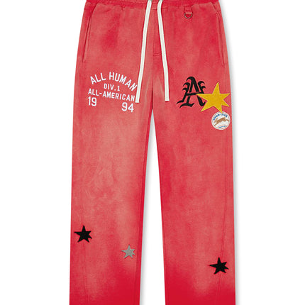 All Human red wash cotton sweatpants featuring collegiate text, a large yellow star, and small black and silver stars.