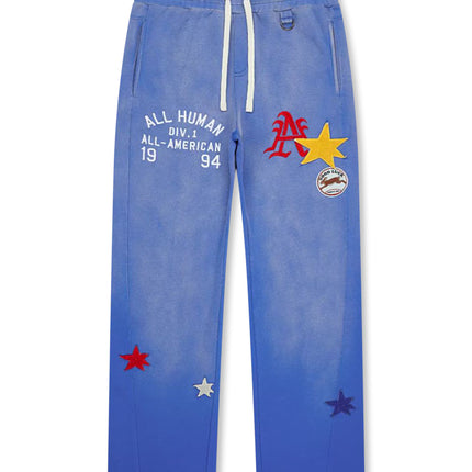 All Human blue-wash cotton fleece sweatpants featuring an embroidered graphic, assorted star patches, and drawstrings.