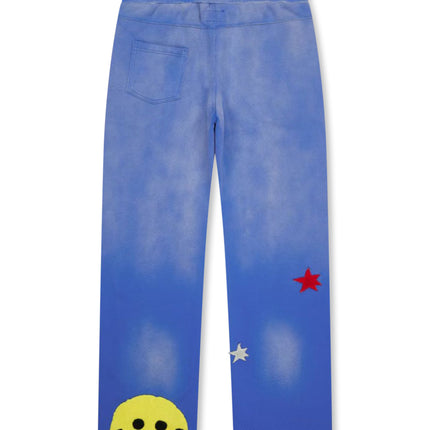 All Human El Perro v2 blue acid-wash sweatpants featuring a yellow stitched smiley face and red and silver star patches.