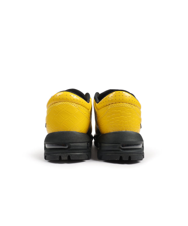 Rear view of vivid sulfur Nike Air Max Goadome Low sneakers featuring yellow crocodile-embossed leather and black soles.
