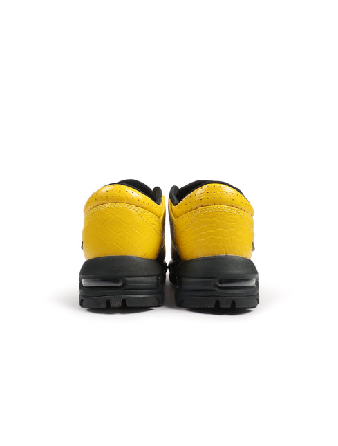 Rear view of vivid sulfur Nike Air Max Goadome Low sneakers featuring yellow crocodile-embossed leather and black soles.