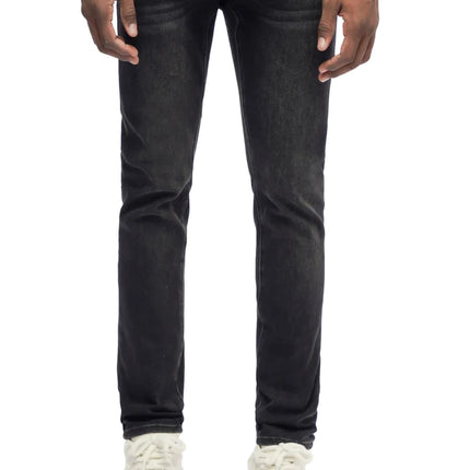 Trnchs Monarch skinny fit jeans in jet black denim with a tapered leg silhouette worn by a standing male model.