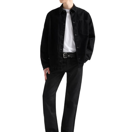 Model wearing 7 For All Mankind Volcano straight jeans in black denim paired with a black button-down shirt and belt.
