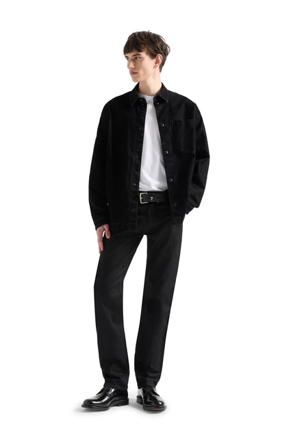 Model wearing 7 For All Mankind Volcano straight jeans in black denim paired with a black button-down shirt and belt.