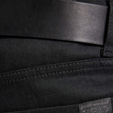 Close-up of black 7 For All Mankind straight jeans featuring a leather belt and branded patch on the denim fabric.