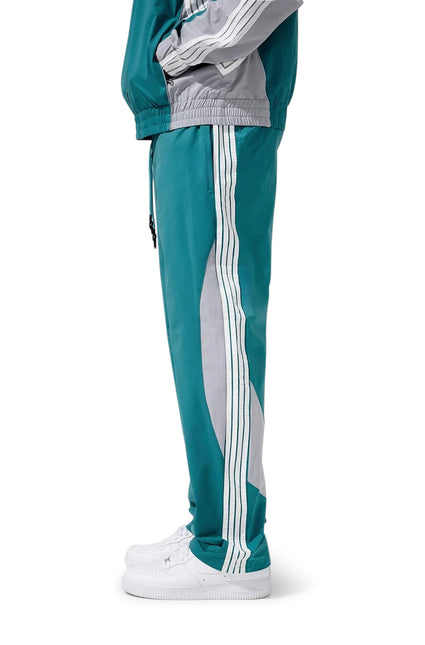 Jordan Craig teal and gray athletic track pants featuring white side stripes and a smooth polyester finish, side view.