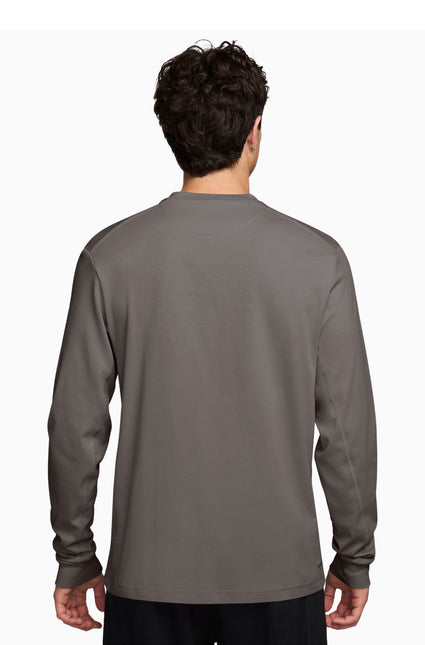 A man viewed from the back wearing a dark gray long-sleeve crewneck shirt, set against a plain white background.