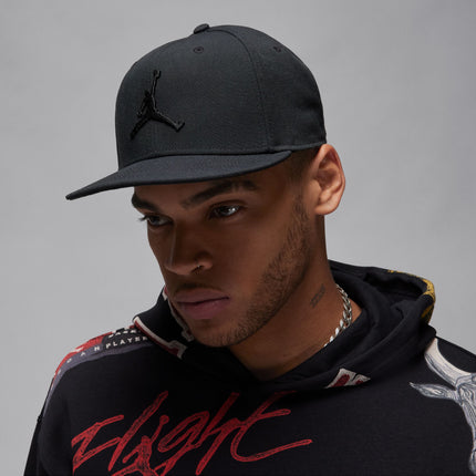 Model wearing a black Jordan baseball cap with a prominent embroidered Jumpman logo against a grey background.