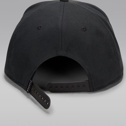 Back view of a black Jordan snapback cap made from a textured woven fabric with an adjustable plastic closure strap.