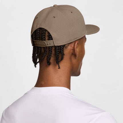 Back view of a person wearing a beige snapback cap with a structured crown and adjustable plastic strap closure.