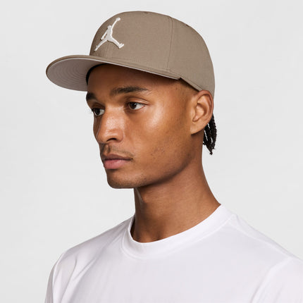 Model wearing a beige Jordan snapback cap with a white Jumpman logo on a structured six-panel cotton fabric base.