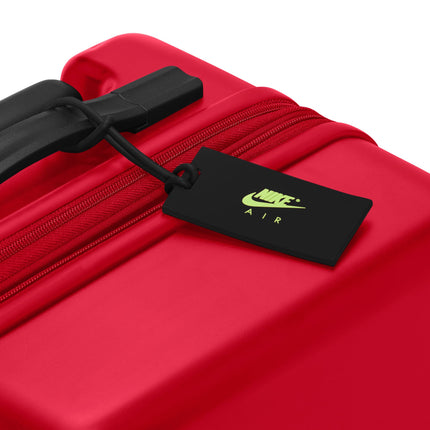 University red hardshell carry-on luggage with a black handle and a black Nike Air branded luggage tag attachment.
