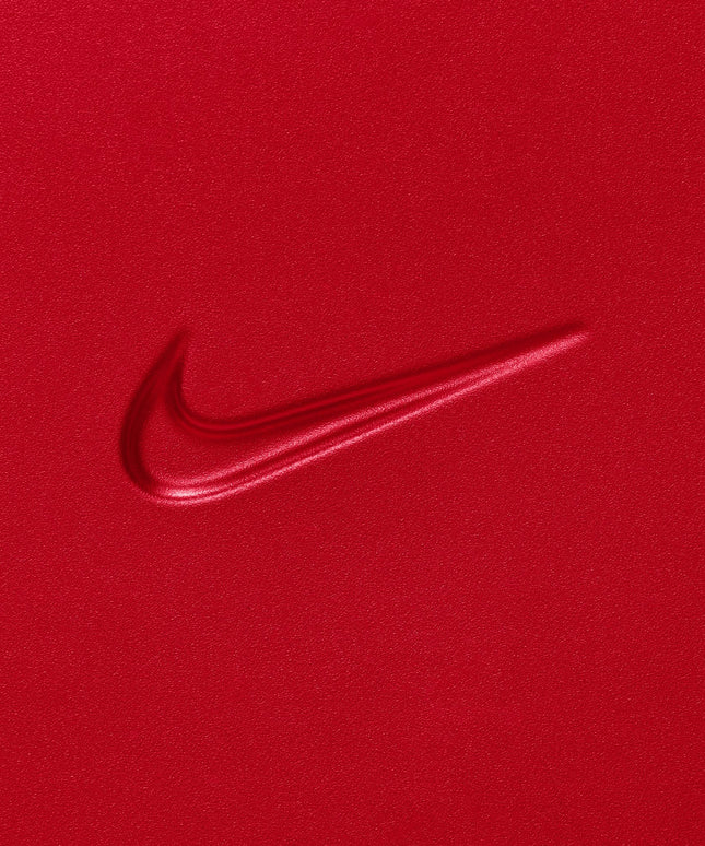 Embossed Nike swoosh logo on a vibrant university red carry-on luggage shell with a smooth, matte textured finish.