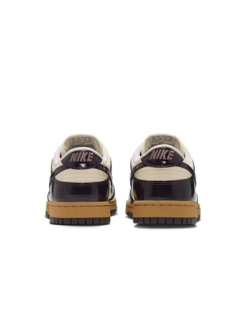Rear view of Nike Dunk Low Retro sneakers featuring glossy dark brown patent leather overlays and coconut milk base.