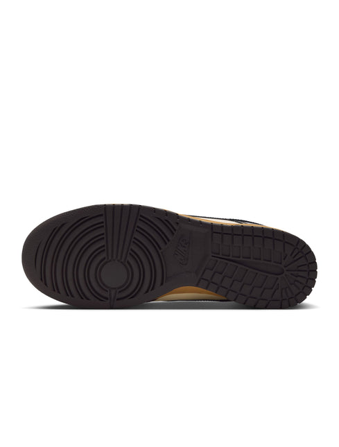 Bottom view of a Nike Dunk Low Retro sneaker featuring a dark brown rubber outsole with a textured grip pattern.