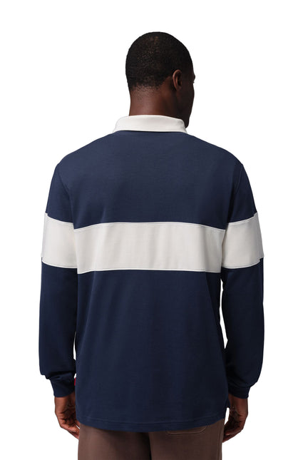 Back view of a man wearing a navy blue Nike Jordan long-sleeve cotton rugby shirt featuring a wide white chest stripe.