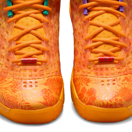 Close-up of Nike Kobe Protro 3 sneakers in safety orange with floral patterns, mesh overlays, and red lace dubraes.