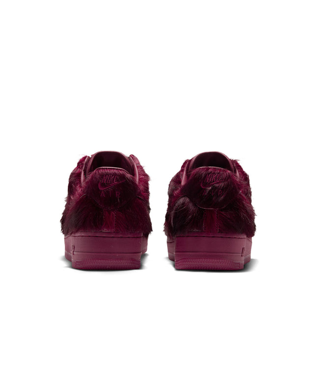 Rear view of Nike Air Force 1 sneakers in Team Red featuring a luxurious faux fur upper and tonal rubber soles.