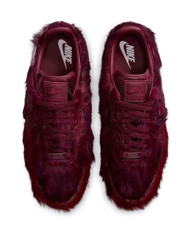 Pair of Nike Air Force 1 sneakers in team red featuring a shaggy, textured faux fur upper, viewed from above.