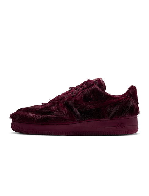 Nike Air Force 1 low-top sneaker in team red faux fur with a matching tonal midsole, shown from a side profile view.
