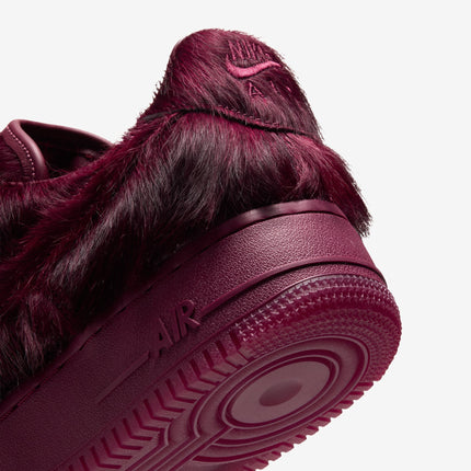 Close-up of a burgundy Team Red Nike Air Force 1 sneaker featuring a shaggy faux fur upper and textured rubber sole.