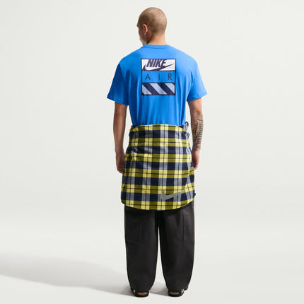 Back view of a man wearing a bright blue Nike Air cotton t-shirt with a checkered yellow and navy shirt tied at waist.