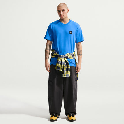 Model wearing a light photo blue Nike Sportswear Air t-shirt with a black and yellow flannel tied around his waist.