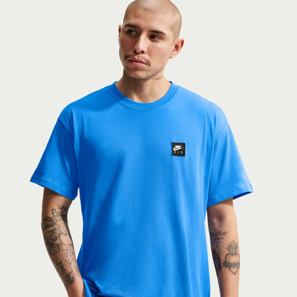 Close-up of a model wearing a vibrant, light photo blue Nike Sportswear cotton t-shirt with a small square Air logo.