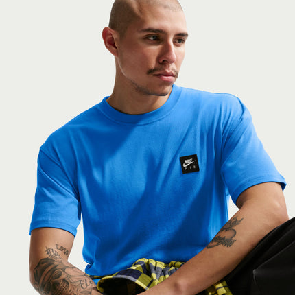 Man wearing a bright light photo blue Nike Sportswear Air cotton t-shirt with a small black square logo patch.