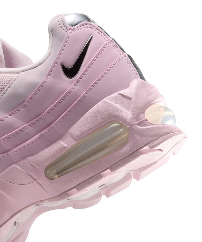 Close-up of a pink foam Nike Air Max 95 sneaker featuring a metallic silver swoosh and glossy chrome heel detailing.