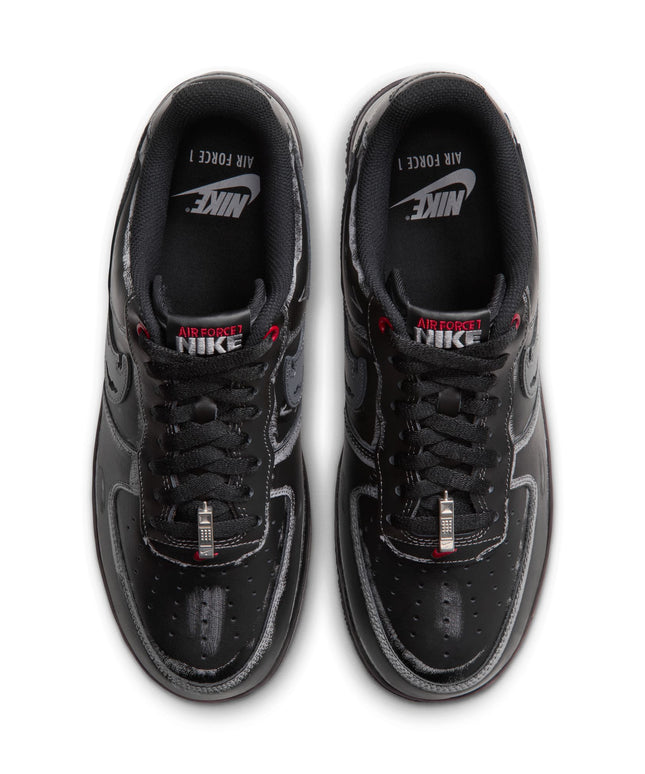 Top view of black Nike Air Force 1 07 sneakers featuring a distressed grey finish, red branding, and metallic dubraes.