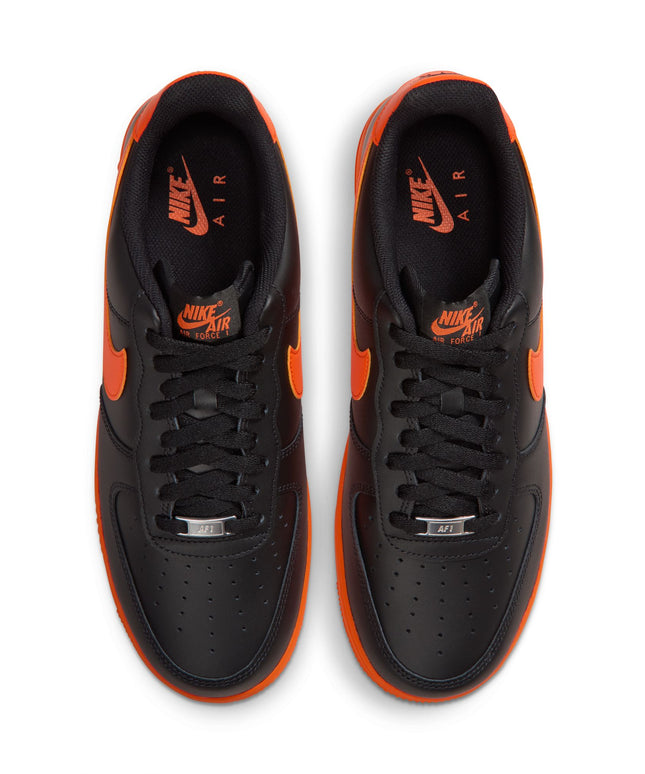 Top view of Nike Air Force 1 '07 sneakers featuring smooth black leather uppers and vibrant orange accents and soles.