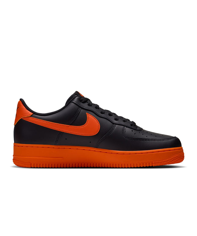 A Nike Air Force 1 Low sneaker in black and orange, shown from a side profile view against a plain white background.