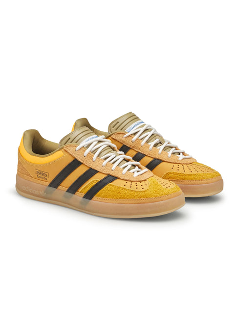 Adidas Bad Bunny Gazelle Indoor sneakers in solar gold suede with black signature stripes, white laces, and gum sole.