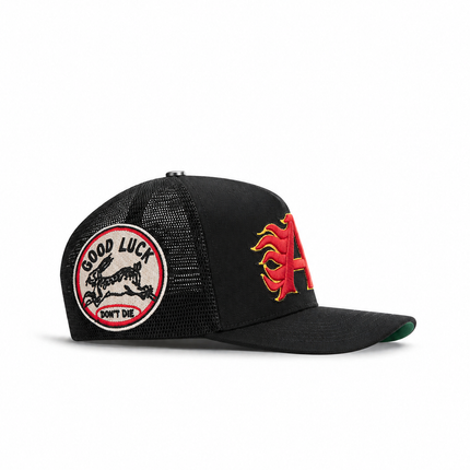 All Human King v2 trucker hat in black featuring a red and yellow flame-style letter A and a Good Luck rabbit patch.