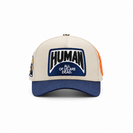 All Human THE CURE baseball cap in cream and navy with a prominent embroidered front patch and text logo.