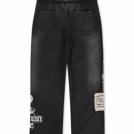 Rebel Minds Jack of All Trades black joggers featuring vintage-style whiskey label patches and distressed graphic print.