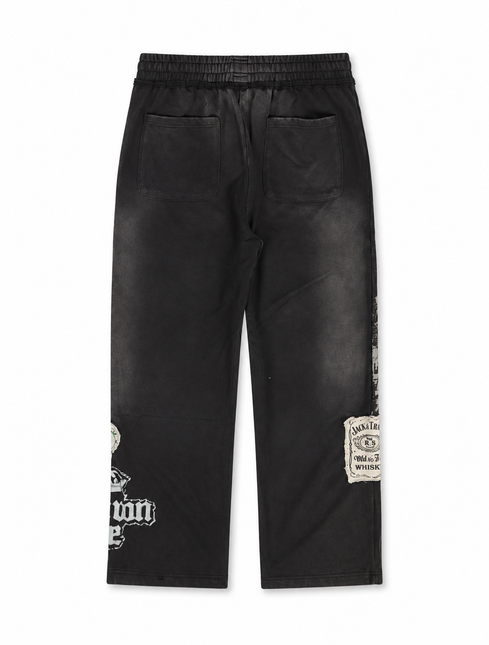 Rebel Minds Jack of All Trades black joggers featuring vintage-style whiskey label patches and distressed graphic print.