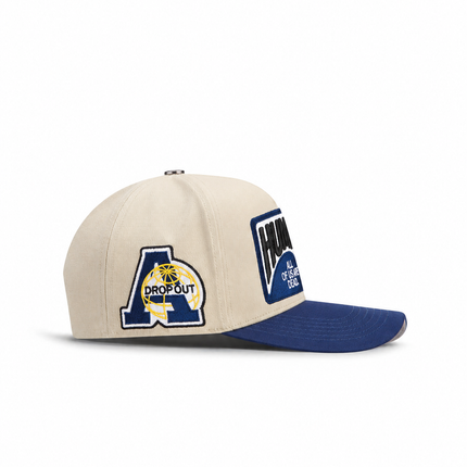 All Human THE CURE cap in cream cotton with a navy blue brim featuring embroidered globe and text patches.